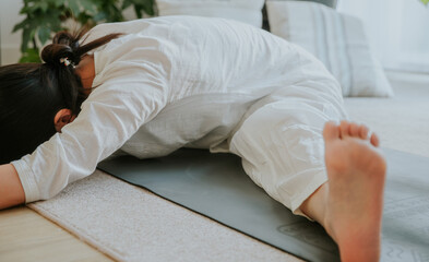 a woman wearing white clothes doing Upavishta Konasana(Wide-Angled Seated Forward Bend) , yoga at home