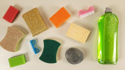Background Cleaning products. Stop motion animation. Kitchen sponges, scrubbing brushes, detergent appear on beige background. Different household cleaning Items. 