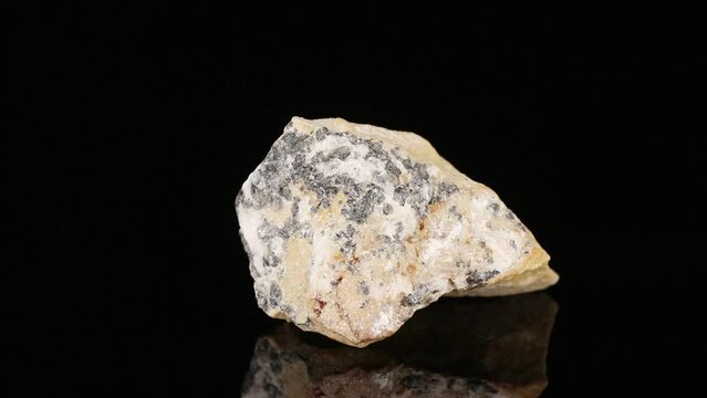 Polished mineral stone chromite rotates in a circle on a black background