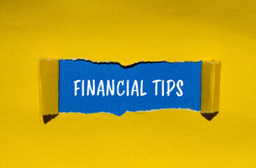 Financial tips words written on ripped yellow paper with blue background. Conceptual financial tips...