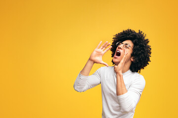 Young african-american man yelling on orange background with empty space