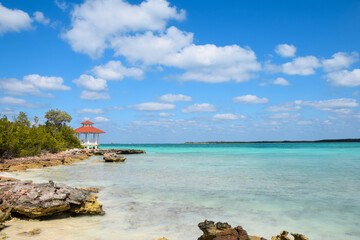 Beautiful tropical ocean rocky shore with turqoiuse blue water and gazebo in the distance