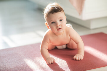 Cute little boy standing on all fours on the floor.  - obrazy, fototapety, plakaty