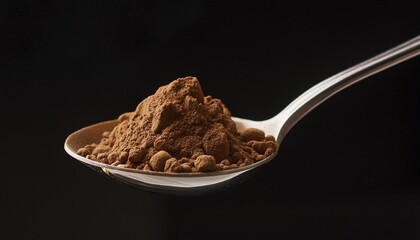 brown powder in a metal spoon on a black background