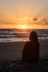 Woman on the beach contemplating the sunrise