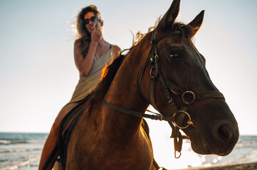 Portrait of a young woman on horseback alongside the summer beach