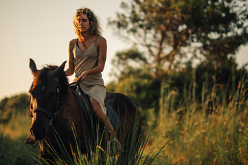 Beautiful young woman horseback riding on coastline in a nature near the beach
