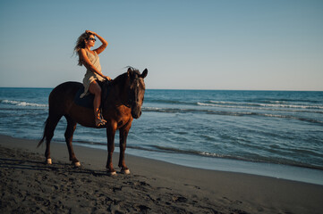 Portrait of a fashionable young woman on horseback alongside the summer beach