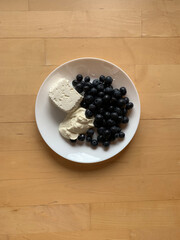A plate with cottage cheese, sour cream and blueberries stands on a wooden background. View from above. Place for text