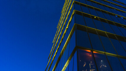 Glass wall of modern high rise office tower under the dusk dark background