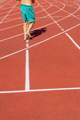 A senior athlete walks barefoot down the training lane at an athletics center in Paris, France, during a sunny diurnal with high temperatures