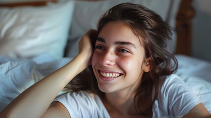 Smiling young woman sitting in bed and looks away