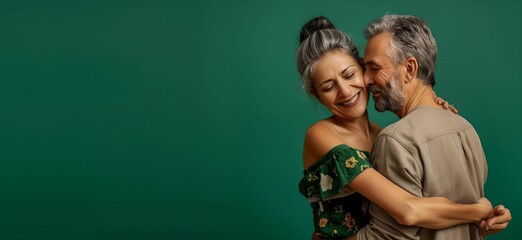 Happy couple over 50 years old in love hugging on a green background. Concept of care, tenderness of love. and connection. Family couple embracing. 