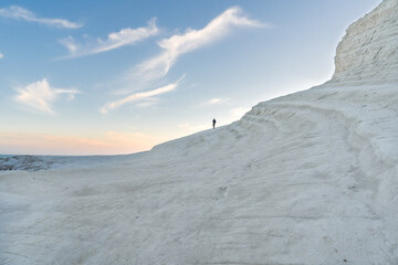 la silhouette d'un homme au bord d'une colline de couleur blanche en bord de Mer au coucher de soleil