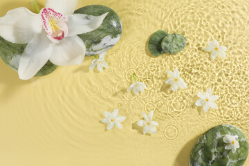 Beautiful flowers and spa stones in water on pale yellow background, top view