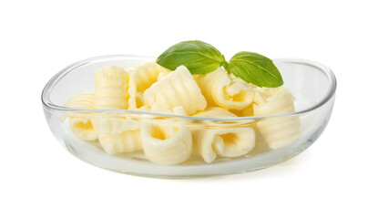 Tasty butter curls and basil leaves in bowl isolated on white