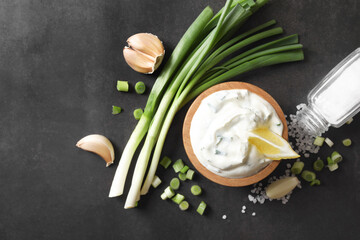 Fototapeta premium Delicious yogurt in bowl, green onion, garlic and salt on black background, flat lay