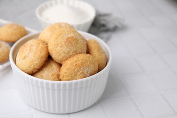 Tasty sugar cookies in bowl on white tiled table, closeup. Space for text