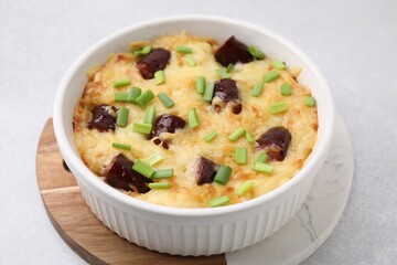 Tasty sausage casserole with green onions in baking dish on white table, closeup