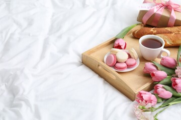 Delicious breakfast, flowers, gift box and card with phrase I Love You on bed, space for text