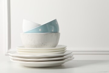 Stack of beautiful ceramic dishware on white table, space for text