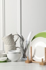 Beautiful ceramic dishware, cups and cutlery on white marble table
