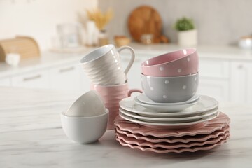 Many different clean dishware and cups on white marble table in kitchen