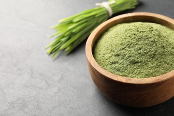 Wheat grass powder in bowl on grey table, closeup. Space for text