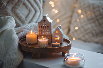 Winter home aromatherapy, cozy atmosphere. Burning aroma candles on wooden tray, knitted blanket....