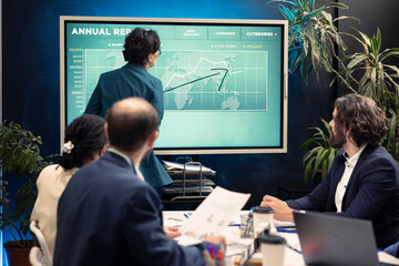 Project manager making a presentation to pitch in a new strategy for company growth, using interactive board to help his team members understand the goal. Business planning meeting in boardroom.