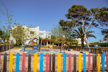  vibrant children's park is nestled amidst colorful wooden fences and towering palm trees, offering...