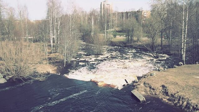 Spring flood. Rushing water in the river, top view. Dark ferrous water rushes in the stream. A yellow-white foam. Karelia, Lososinka River in spring. Floods, tsunami and climate change. Water movement
