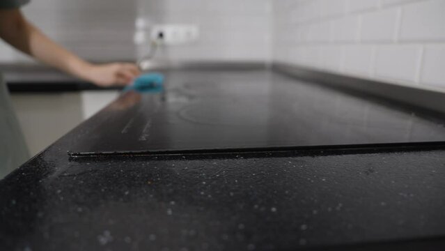 Housewife cleaning dirty kitchen stove with hot wet steam using an electric steam cleaner. Cleanliness and housekeeping concept. Cleaning the hob with hot steam, close-up.