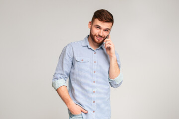 Glad to hear you. Portrait of smiling man talking on phone on studio background, panorama, copy...
