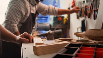 Woodworker using power drill to create holes for dowels in wooden board, close up. Carpenter sinks...