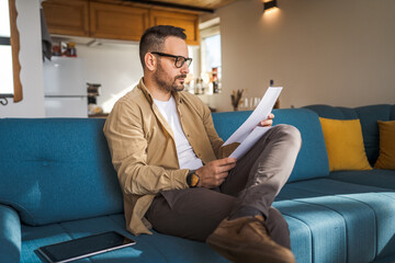 Adult man with eyeglasses read and watch document work at home