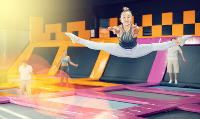 Adult sports woman training to do jumps in trampoline center