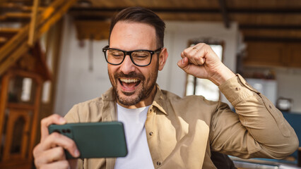 Adult man with eyeglasses play video games on his phone at home