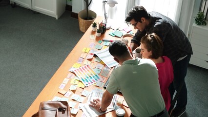 Top view of smart designer holding color palette while project manager looking at design and choosing color for program. Professional businesswoman taking a note while design creative logo. Symposium.