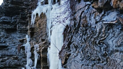 Mountain Water Spring Cascade Frozen into Ice Stalactites on Rocky Wall