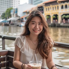 This portrait showcases a young Indonesian woman enjoying a bubble tea by the river at Clarke Quay, Singapore. Her smile and the scenic urban backdrop create a perfect blend of leisure and city life.