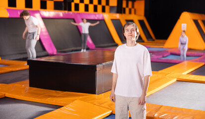 Positive young man wearing sport clothes standing expressing different poses in trampoline arena