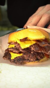 hand wraping a triple cheeseburger with cheese