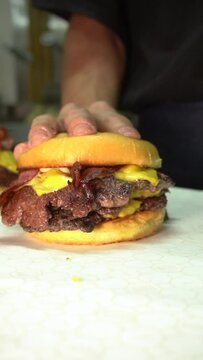 chef preparing food in restaurant, bun in a doble cheeseburger with bacon