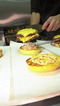 chef preparing food, stacking a doble cheese burger in the bun