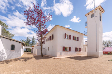 White facades of an Andalusian cortijo style country house with red wooden shuttered windows and...