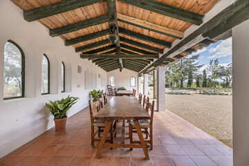 Wooden dining tables in a gallery with wooden ceilings in the patio of an Andalusian farmhouse style house