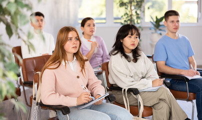 Young female student listening to lecture with focus