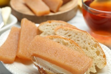 Delicious quince paste and bread on table, closeup
