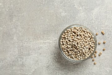 Aromatic spice. White pepper in bowl on light grey table, top view. Space for text